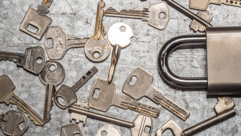 Diverse sleutels en een hangslot op een metalen ondergrond, passend bij sleutel bijmaken Weert