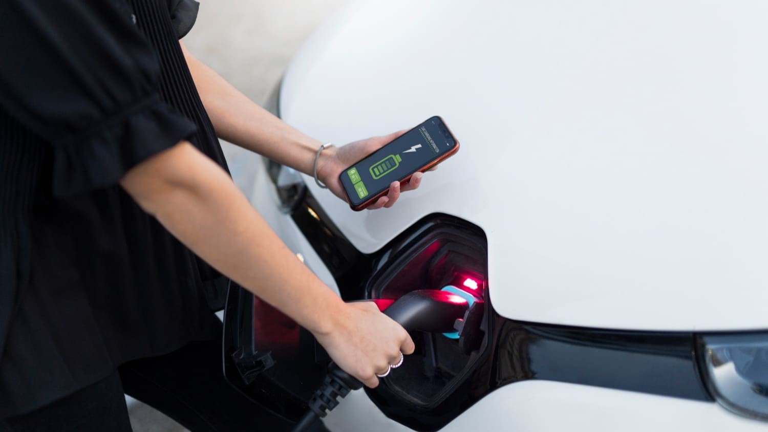 Vrouw laadt elektrische auto op terwijl ze het laadproces volgt via een app, bijtelling elektrische auto inzichtelijk