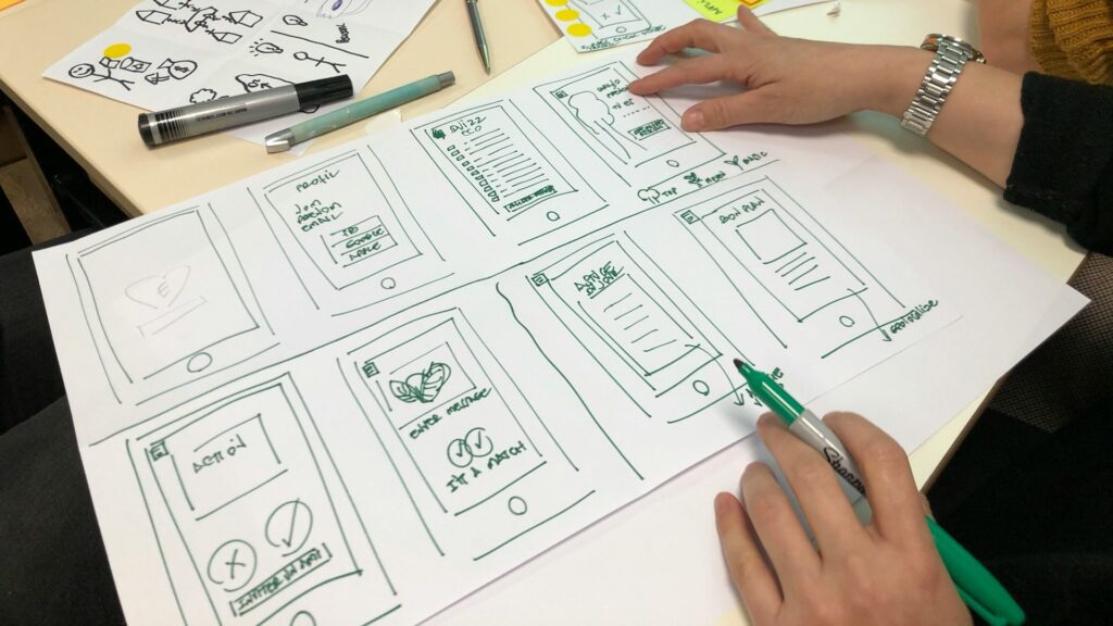 Schets van app-ontwerp waarin een idee visueel wordt uitgewerkt met wireframes en notities.