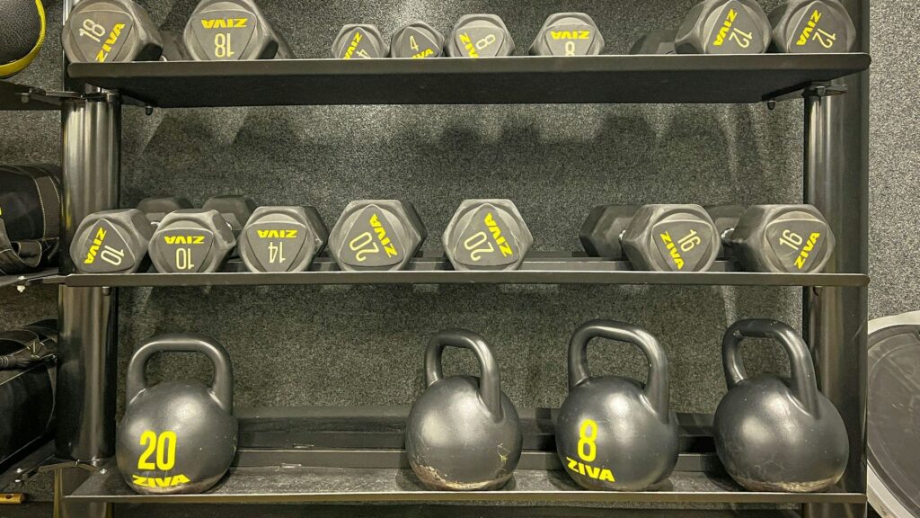 Set dumbbells en kettlebells op een rek, onderdeel van een thuis krachtopstelling