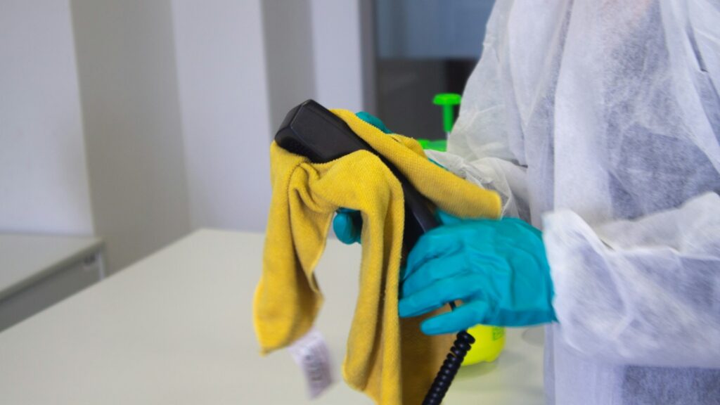 Industriële schoonmaak van telefoon met gele doek en handschoenen
