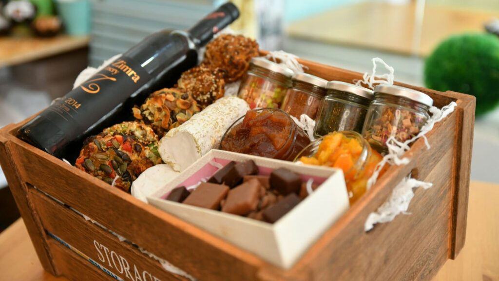Zelf samengesteld cadeau met luxe hapjes en wijn in houten kist als persoonlijk geschenk