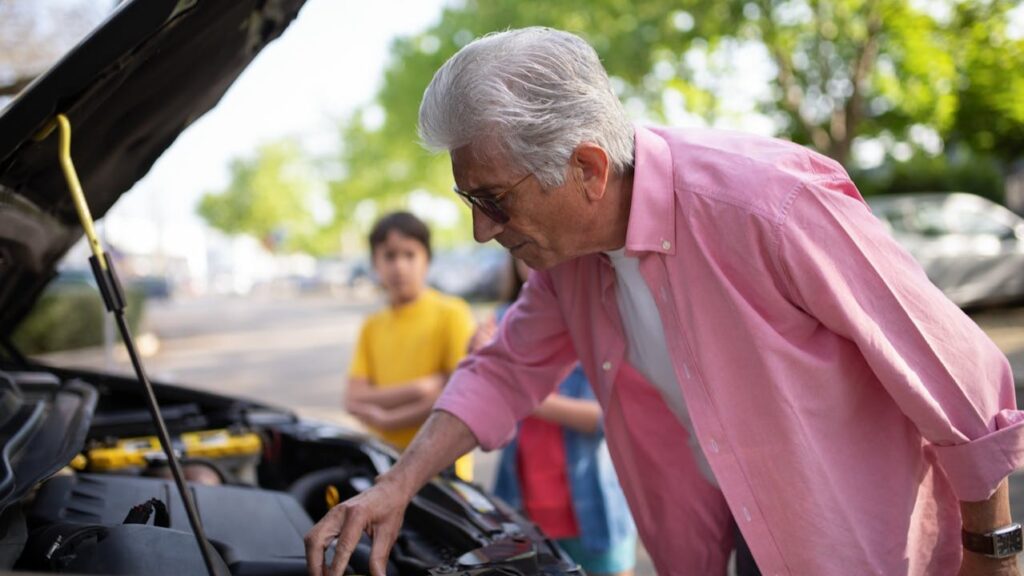 Autopech veilig handelen waarbij bestuurder motor inspecteert terwijl anderen op afstand blijven bij de auto
