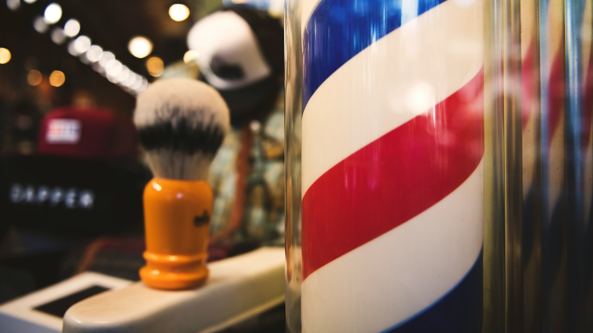 Barbershoppaal met rood-wit-blauwe strepen naast een scheerkwast – symbool voor een thuissalon starten