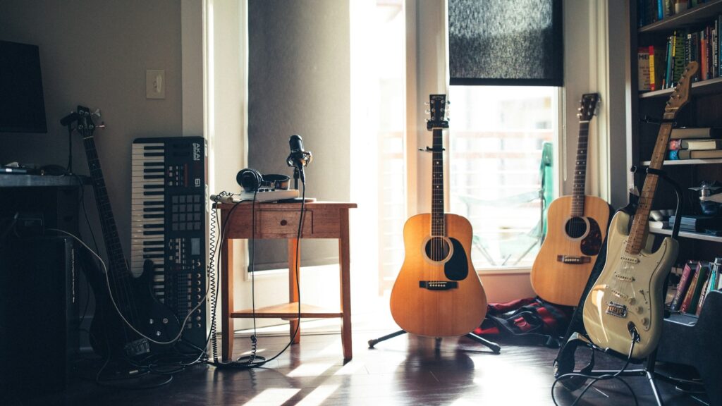 Gitaarakkoorden leren in thuisstudio met akoestische en elektrische gitaren naast werkplek