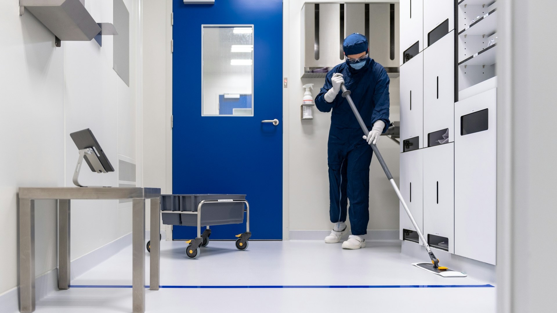 Persoon in beschermende kleding voert industri&euml;le schoonmaak uit in steriele ruimte